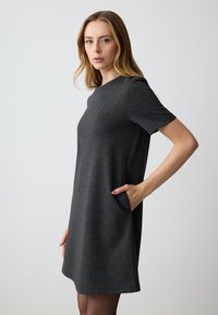 Korte mouwen antracietgrijze jurk van zachte stof, met een ronde halslijn en zijzakken. Gladde textuur met een relaxed fit.