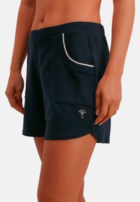 Donkerblauwe short van zachte stof, voorzien van een wit afgezette zak en een klein geborduurd ontwerp bij de zoom, met een losse pasvorm.