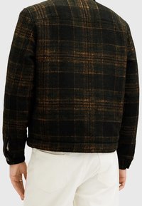 Černá a oranžová kostičkovaná bunda z texturované vlny, s krátkým, boxy střihem a knoflíkovými manžetami. Zobrazena zadní strana.