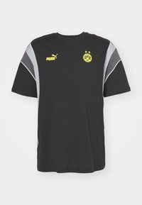 Svart t-shirt med kort ärm och grå sidosträck, med en gul Puma-logotyp och en Borussia Dortmund-badge på bröstet.