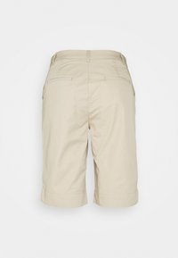 Beige Baumwollshorts mit geradem Schnitt, umgeschlagenem Saum und zwei Details an den Gesäßtaschen. Einfaches Design ohne sichtbare Verschlüsse oder Muster.