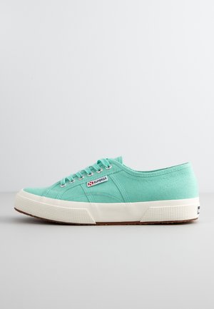 Baskets en toile vert menthe clair avec semelle en caoutchouc blanc, talon texturé contrasté et trois œillets pour les lacets. Présente une étiquette de logo.