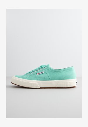 Jasno miętowe płócienne trampki z białą gumową podeszwą, kontrastującym teksturowanym obcasem i trzema otworami na sznurówki. Posiadają metkę z logo.