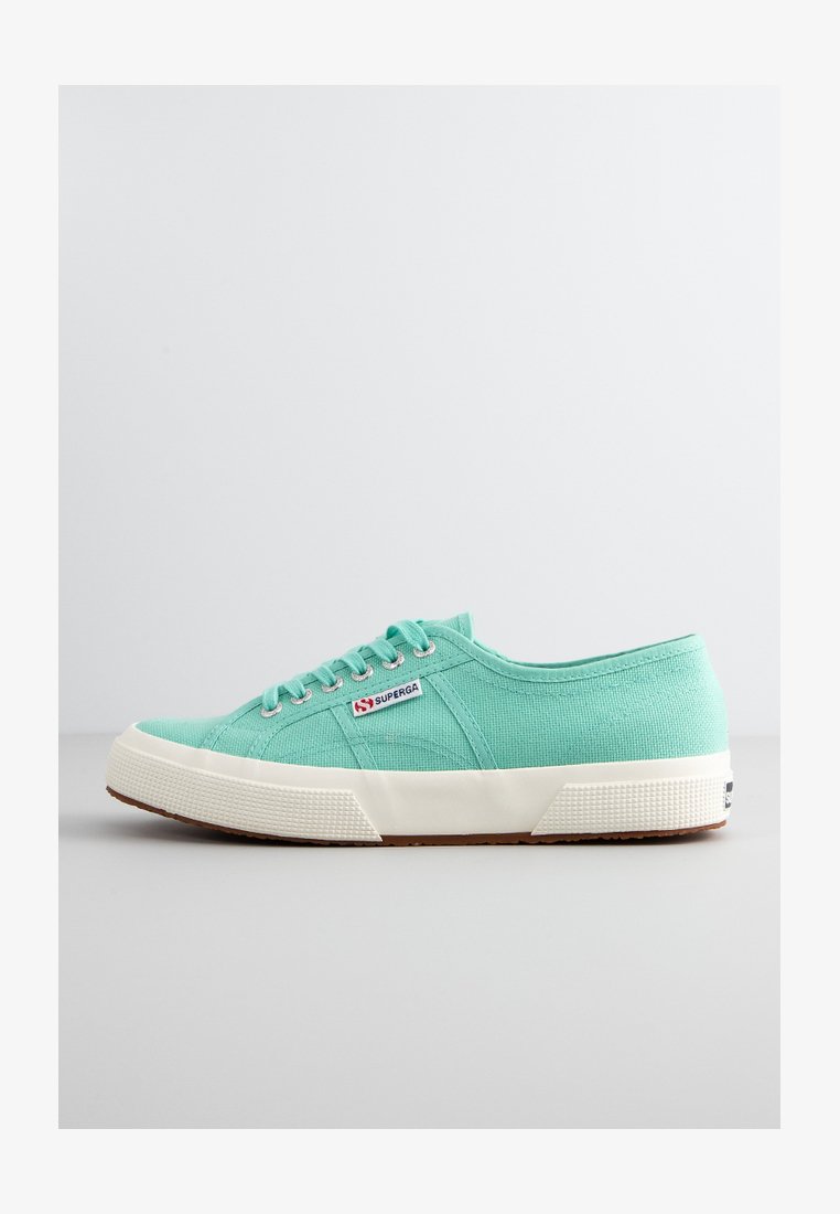 Jasno miętowe płócienne trampki z białą gumową podeszwą, kontrastującym teksturowanym obcasem i trzema otworami na sznurówki. Posiadają metkę z logo.