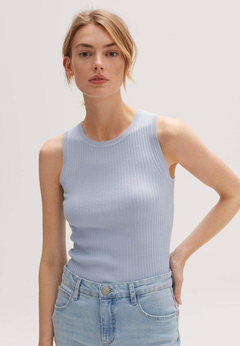 Light blue ribbed tank top with a round neckline, sleeveless design, and a fitted shape, paired with light wash denim jeans.