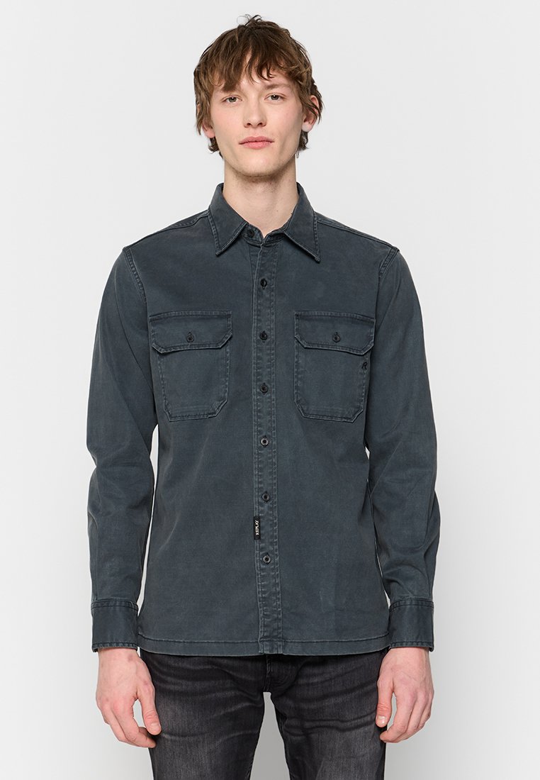 Dunkelgraues Hemd mit Knopfverschluss, strukturiertem Kragen, zwei Brusttaschen und langen Ärmeln. Hergestellt aus einem weichen, strukturierten Material.