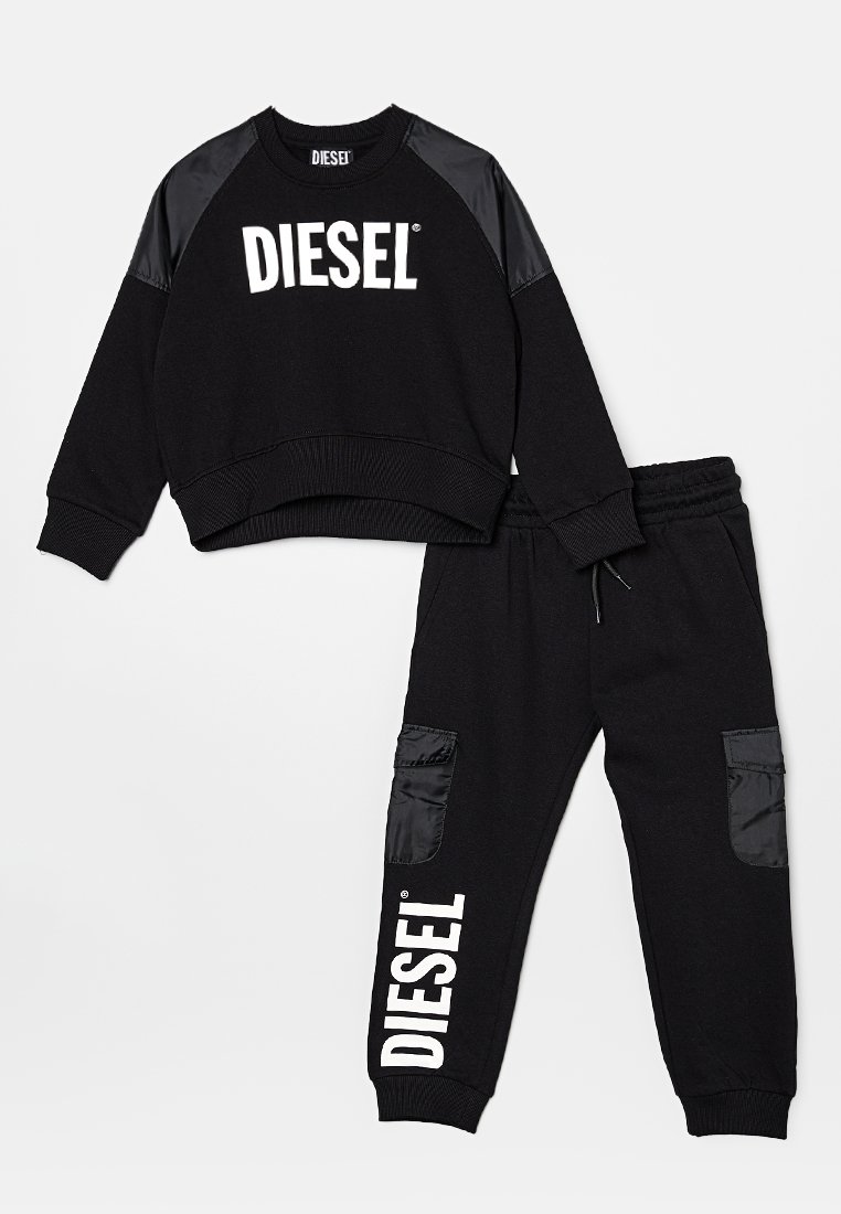 Sweatshirt noir et pantalon de survêtement assorti en coton, avec des panneaux d'épaule brillants noirs et des poches latérales. Affiche un grand logo blanc "DIESEL".