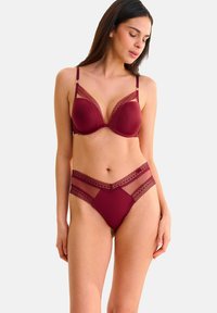 Ensemble soutien-gorge bordeaux et culotte taille haute avec des accents en dentelle translucide, des bonnets plongeants et des bretelles réglables pour un ajustement et un confort optimaux.