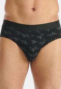Męskie slipy w kolorze czarnym z wzorem ciemnozielonych, geometrycznych kształtów. Posiadają jednolity czarny pas w talii i gładką fakturę.