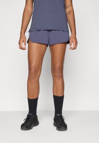 Navy shorts with curved hem and soft texture, paired with a matching navy tank top, black athletic shoes, and black crew socks.
