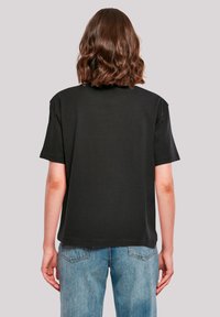 Black short-sleeve T-shirt with a relaxed fit. Smooth cotton fabric with a round neckline and dropped shoulders. Paired with light blue denim jeans.