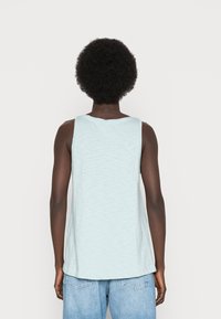 Lichtblauw tanktop van zachte stof, met een ronde halslijn en een losse pasvorm, met een iets gebogen zoom aan de achterkant.