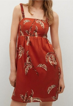 Robe d'été rouge avec un corsage ajusté, une jupe évasée et un motif floral de feuilles en crème et marron. Elle présente des bretelles étroites et des détails froncés.