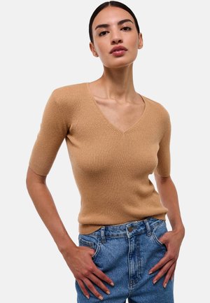 Haut en maille côtelée à manches courtes de couleur kaki avec un décolleté en V. Associé à un jean en denim taille haute, présentant un style classique à cinq poches.