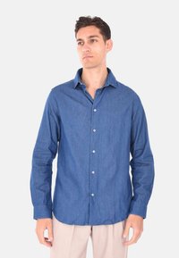 Camicia in denim con bottoni, maniche lunghe, colore blu, colletto standard, bottoni bianchi, orlo dritto, vestibilità casual. Texture morbida, senza fantasie.