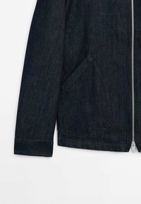 Dark blue denim jacket featuring a zip front, large angled pocket, and cuffed sleeves. Smooth texture with a classic design.