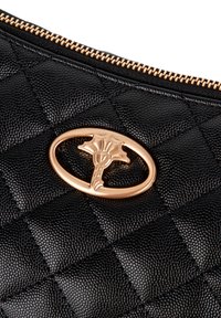 Sort quiltet læderclutch med guldlynlås og ovalt beslag med et dekorativt palmedesign i midten.