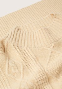 Pull tricoté couleur crème avec encolure ronde côtelée et détails en maille texturée et à motifs.