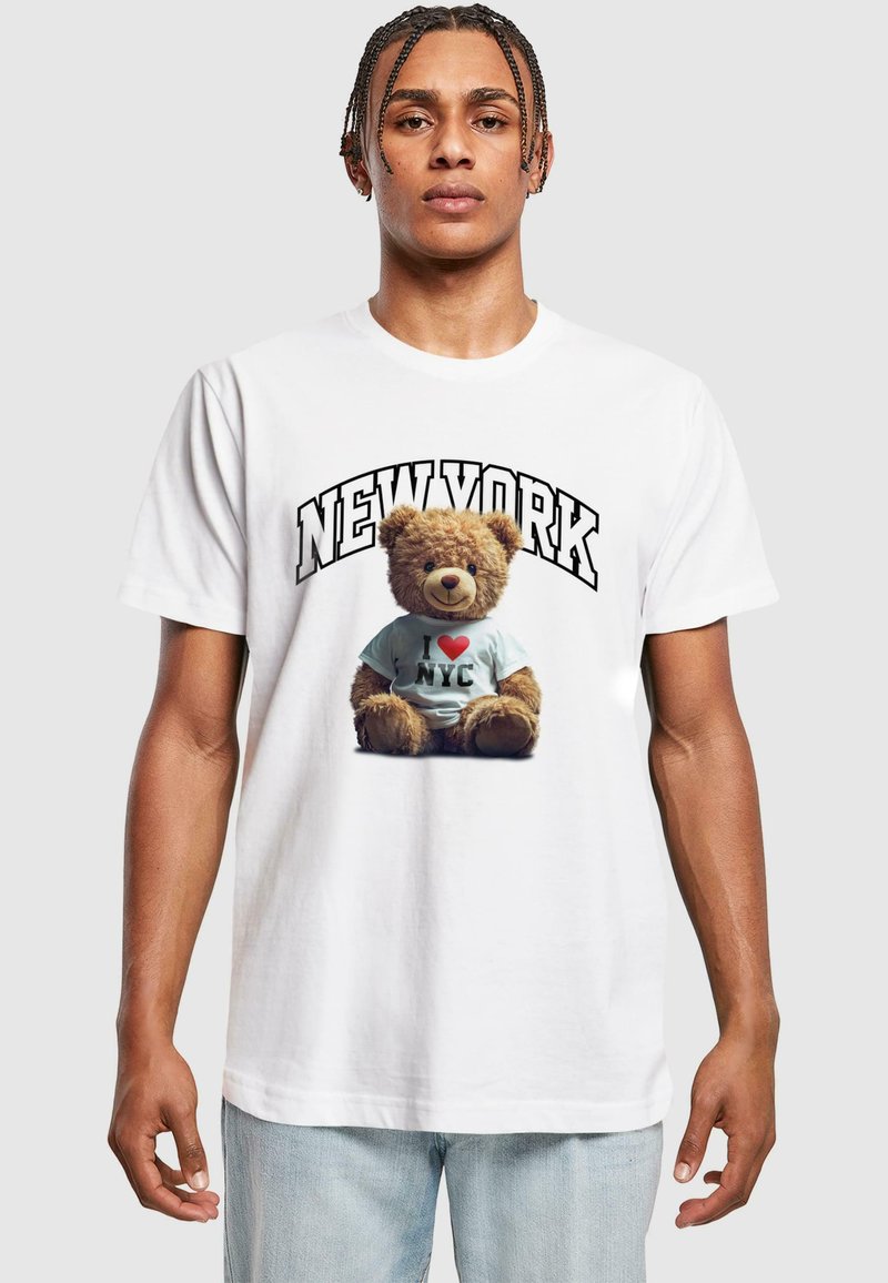 Hvitt bomull T-skjorte med grafikk av en bamse som har på seg en lyseblå "I ❤️ NYC" T-skjorte, med teksten "NEW YORK" over.