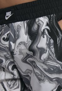 Kraťasy Nike s černým elastickým pasem a vířícím mramorovým vzorem v odstínech šedé a bílé. Lehká, hladká textura.