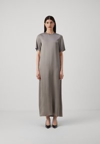 Rochie lungă din satin gri deschis, cu mâneci scurte, decolteu rotund și siluetă dreaptă. Purtați cu tocuri negre cu vârf ascuțit.