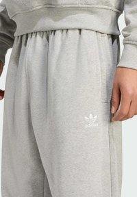 Light gray, cotton blend sweatpants with an elastic waistband, side pockets, and a white Adidas logo on the left leg.