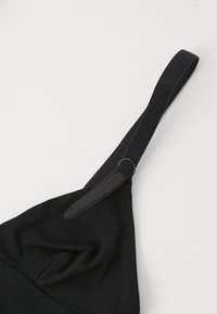 Μαύρο βαμβακερό σουτιέν με τριγωνικά cups, ρυθμιζόμενο λουρί που διαθέτει λεία υφή και μια υφασμάτινη περιοχή κοντά στο σημείο προσάρτησης.