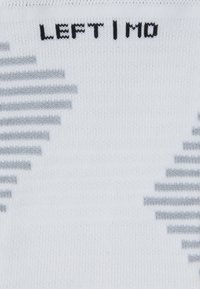 Meia branca com riscas horizontais em preto e cinza, apresentando o texto "ESQUERDA | MO" em letras grandes pretas. Textura suave e tricotada.