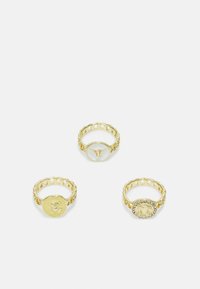 Conjunto de três anéis em tom dourado com configurações circulares. Um tem um logotipo, outro apresenta um design de urso e o último está adornado com strass.