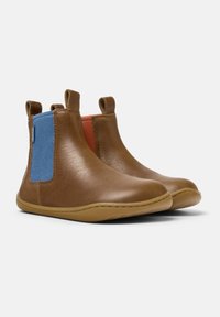 Botas de tobillo de cuero marrón con acentos de tela azul y roja, punteras redondeadas y lengüetas en los laterales. Textura suave con una suela flexible.