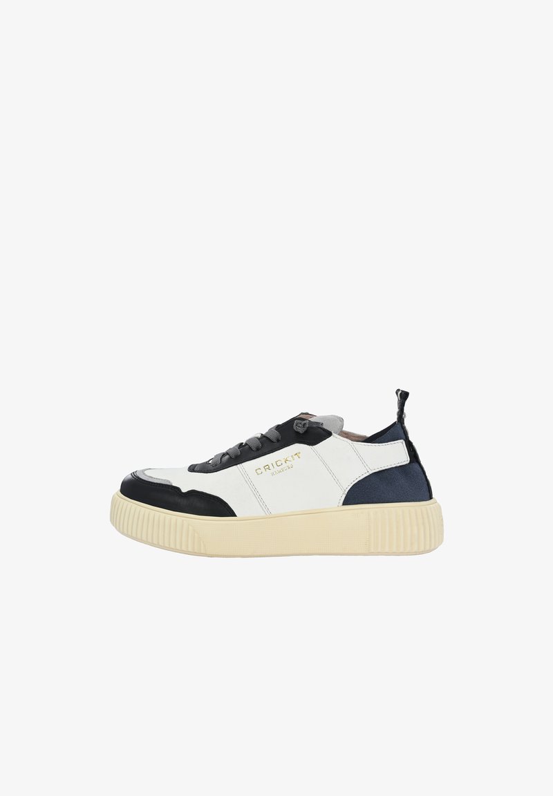 Sneaker bianco e nero con una suola texturizzata e rigata. Presenta un logo dorato, una chiusura con lacci e accenti blu navy a contrasto sul retro.
