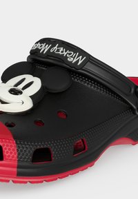 Μαύρο και κόκκινο παπούτσι τύπου κλογκ με διακόσμηση το πρόσωπο του Μίκυ Μάους στην κορυφή και ρυθμιζόμενο λουράκι στο τακούνι με την ένδειξη "Mickey Mouse".