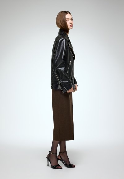 Black leather biker jacket with zippers, paired with a brown knee-length skirt and black strappy high heels. Smooth textures, fitted silhouette.