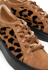 Sneakers in suede con un design a stampa leopardata in marrone e nero, con lacci in velluto beige e una suola piatta nera spessa.