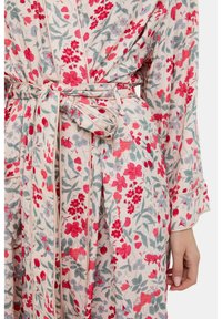 Floraler Kimono aus leichtem Stoff mit roten und blauen Blumen auf cremefarbenem Hintergrund, mit gebundenem Gürtel und langen Ärmeln.