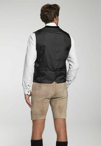 Schwarze Weste aus strukturiertem Stoff, weißes Hemd, beige Shorts und schwarze Kniestrümpfe; verfügt über einen Verschluss und ein tailliertes Rückendesign.