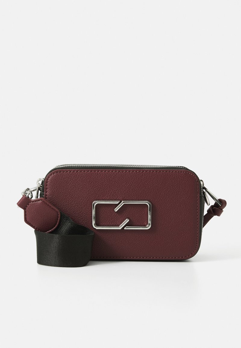 Sac bandoulière en cuir bordeaux de forme rectangulaire, avec quincaillerie en argent, surface texturée et une bandoulière noire amovible.