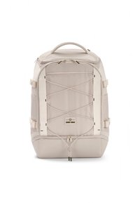 Jasnobeżowy plecak z teksturowanej tkaniny, wyposażony w przedni sznurek bungee, boczne paski oraz górną rączkę ułatwiającą przenoszenie.