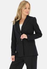 Czarny żakiet w prążki o dopasowanym kroju, z pojedynczym zapięciem na guzik i klapami w kształcie litery notch; posiada dwie kieszenie z przodu oraz teksturowaną tkaninę.