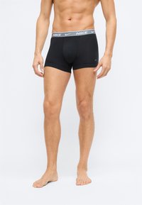 Černé boxerky vyrobené z bavlny, s těsným střihem. Mají šedý elastický pásek s logem "Nike". Jednoduchý design, bez viditelných vzorů.