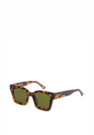 Lunettes de soleil carrées avec une monture en écaille de tortue et des verres verts. Les caractéristiques incluent une marque bien en vue sur les branches et une finition polie.