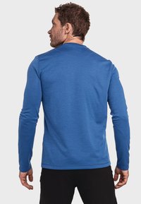 Langärmliges blaues Hemd aus einem strukturierten Stoff, mit rundem Halsausschnitt und taillierter Passform, von hinten präsentiert.