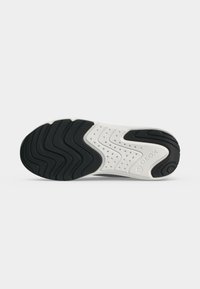 Semelle de basket noire et blanche avec des motifs ondulés, des perforations au centre et le nom de la marque Geox en relief sur le côté.