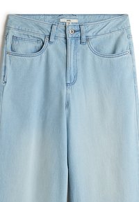 Jeans in denim leggero di colore blu chiaro con vita alta, dotati di passanti per la cintura, tasche frontali e un singolo bottone in metallo. Texture liscia e design classico.