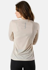 Lichtbeige sportieve long-sleeve top, met een gestructureerde stof, slim fit en een zichtbaar logo op de bovenrug.