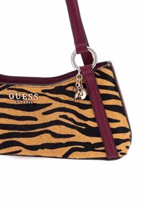 Borsa a tracolla con motivo tigre marrone e nero, dotata di una tracolla in pelle bordeaux, caratterizzata da un logo argentato e charm. Superficie in pelliccia testurizzata con accenti eleganti.