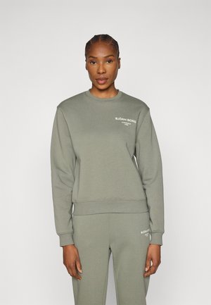 Ανοιχτό πράσινο φούτερ από μαλακό ύφασμα, με στρογγυλή λαιμόκοψη, μακριά μανίκια, ριμπ μανσέτες και το λογότυπο "BJÖRN BORG" στο στήθος.