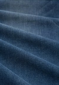 Donkerblauwe denimstof met een gladde textuur en subtiele kleurvariaties, met een klassiek keperbindpatroon.