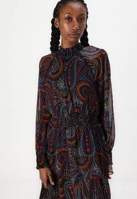 Vestido de manga longa escuro com padrão paisley com detalhes em vermelho, laranja e azul; cintura elástica e gola alta com detalhe franzido.