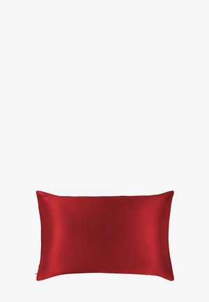 Oreiller en soie rouge, forme rectangulaire, texture lisse, branding discret visible sur un côté. Design épuré sans motifs ni accents.